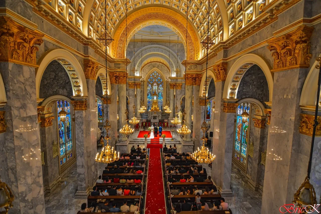 An ornate interior with golden arches and a vivid red aisle.