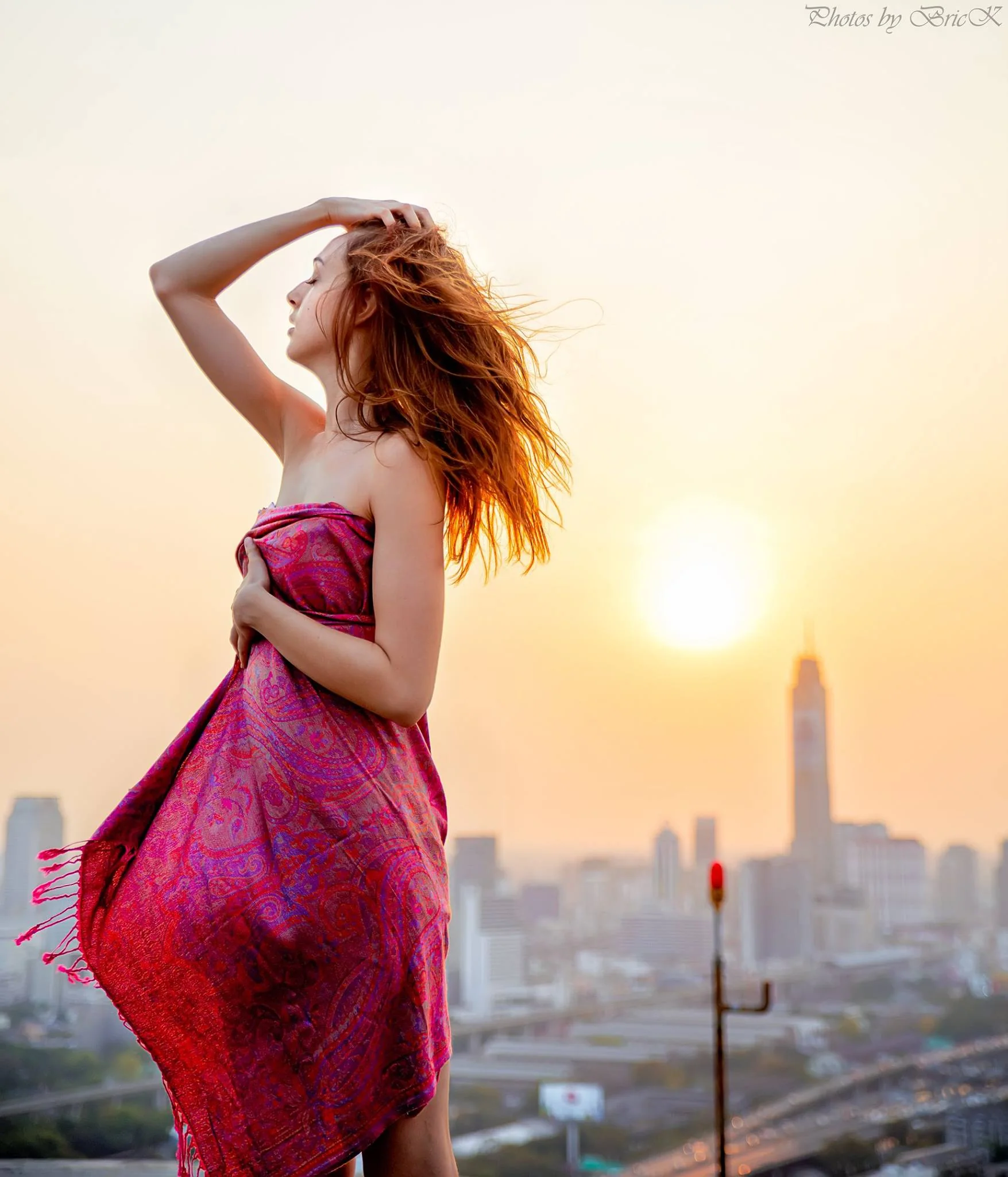Pink fabric, windblown hair and golden light above the city.