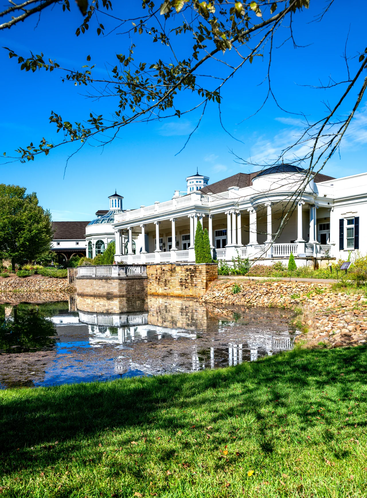 A grand white-columned building stands beside a reflecting pool.