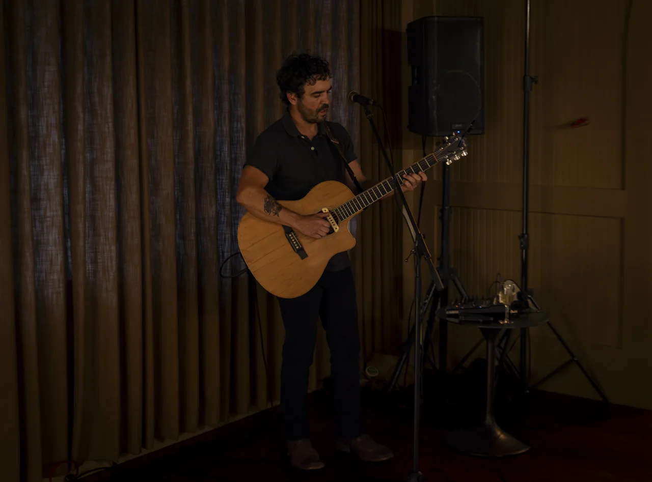 A musician plays guitar beside a microphone in a restaurant.