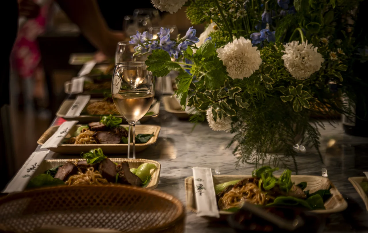 Flowers and small lamps run along a long dining table.