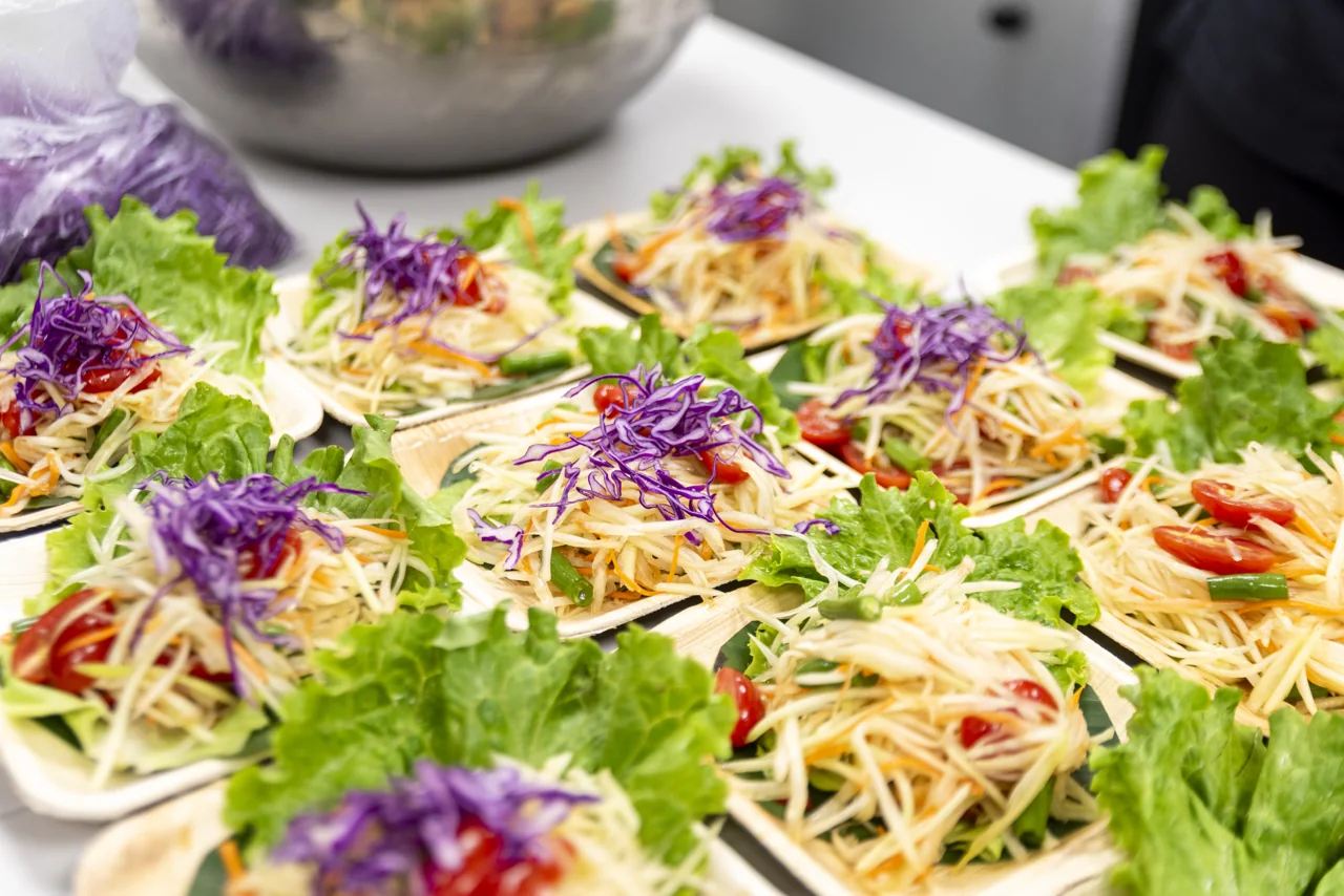 Bright salad leaves and purple flowers fill a tray of prepared dishes.