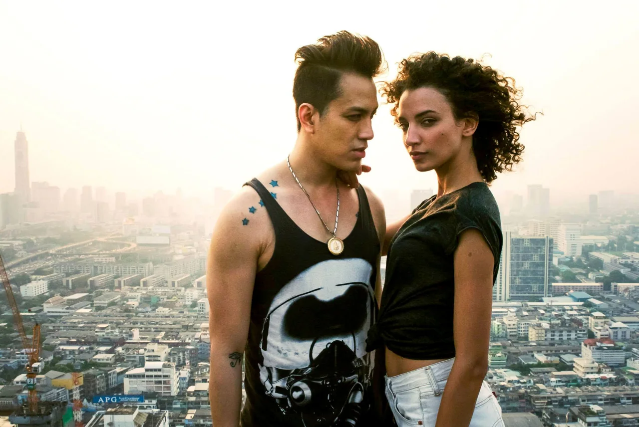 Two people stand side by side on an urban rooftop.