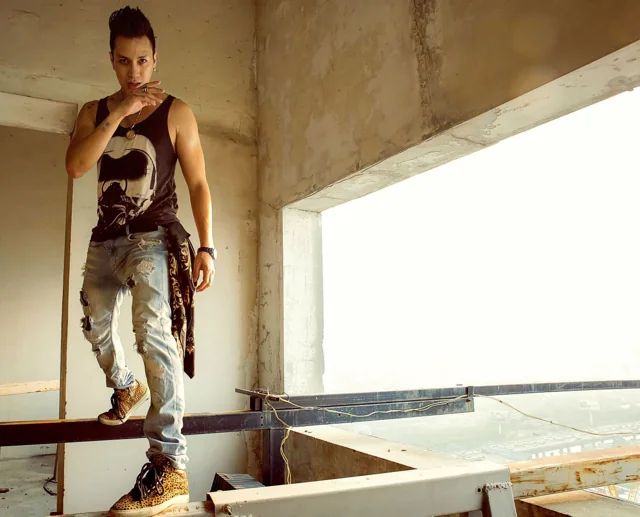 A man poses in a bare concrete architectural opening.