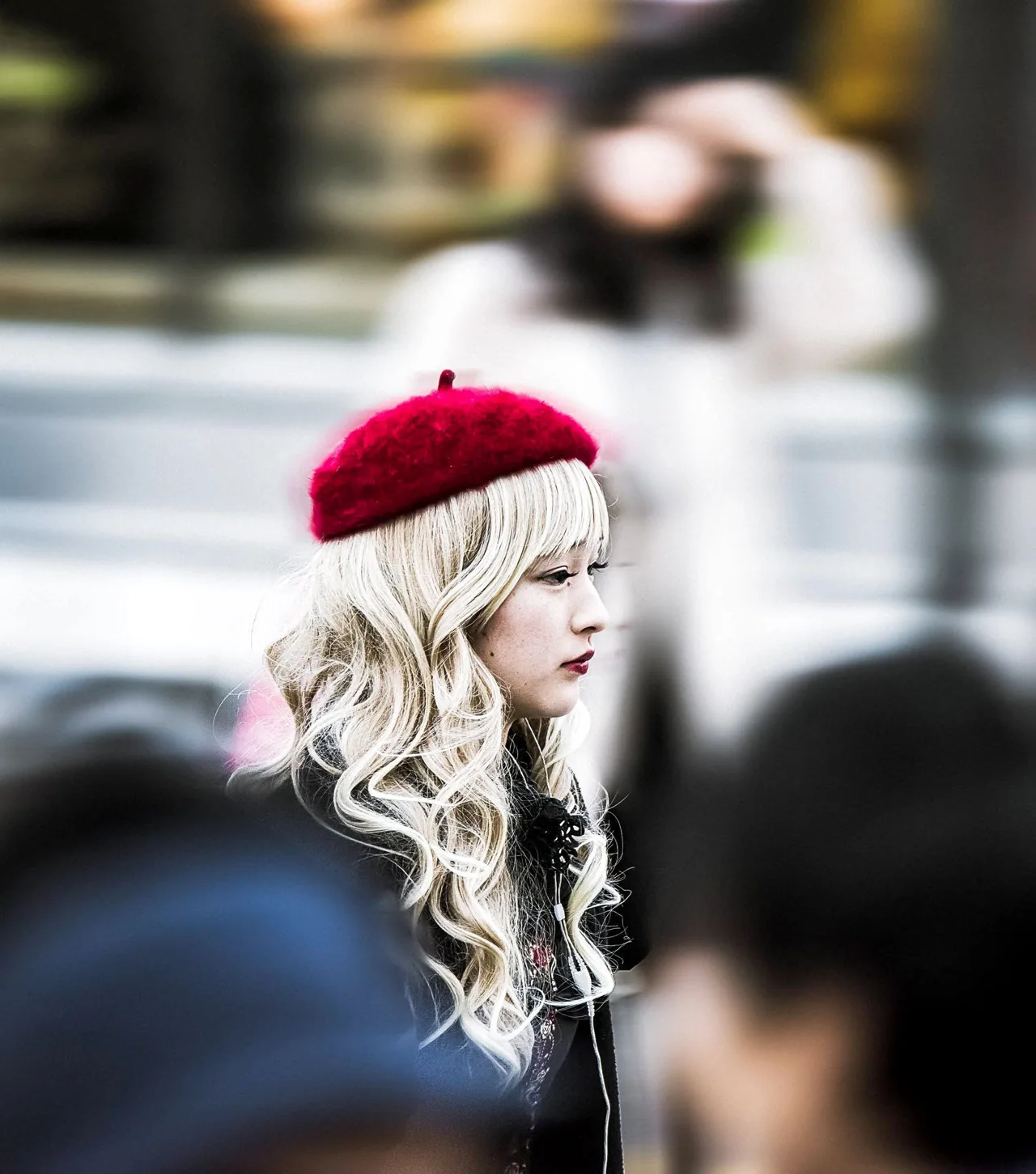 A woman wears a red hat in an outdoor street portrait.