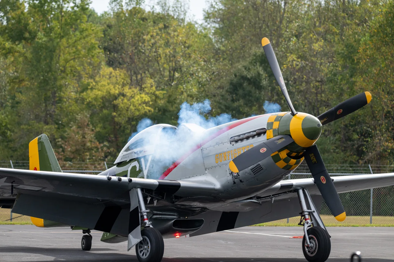 Smoke rises as the propeller of a vintage aircraft starts.