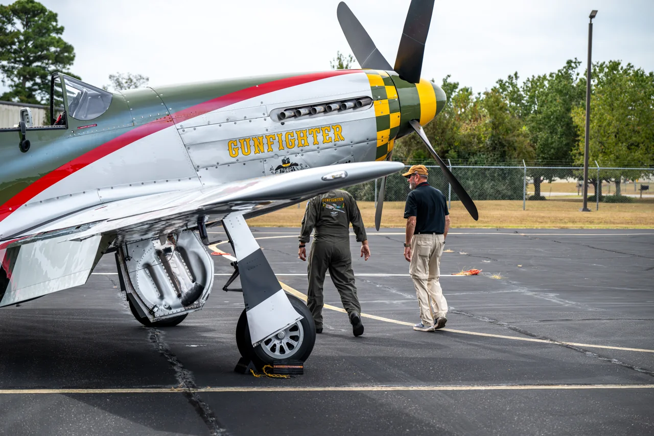 A person walks toward the camera beside a vintage aircraft.