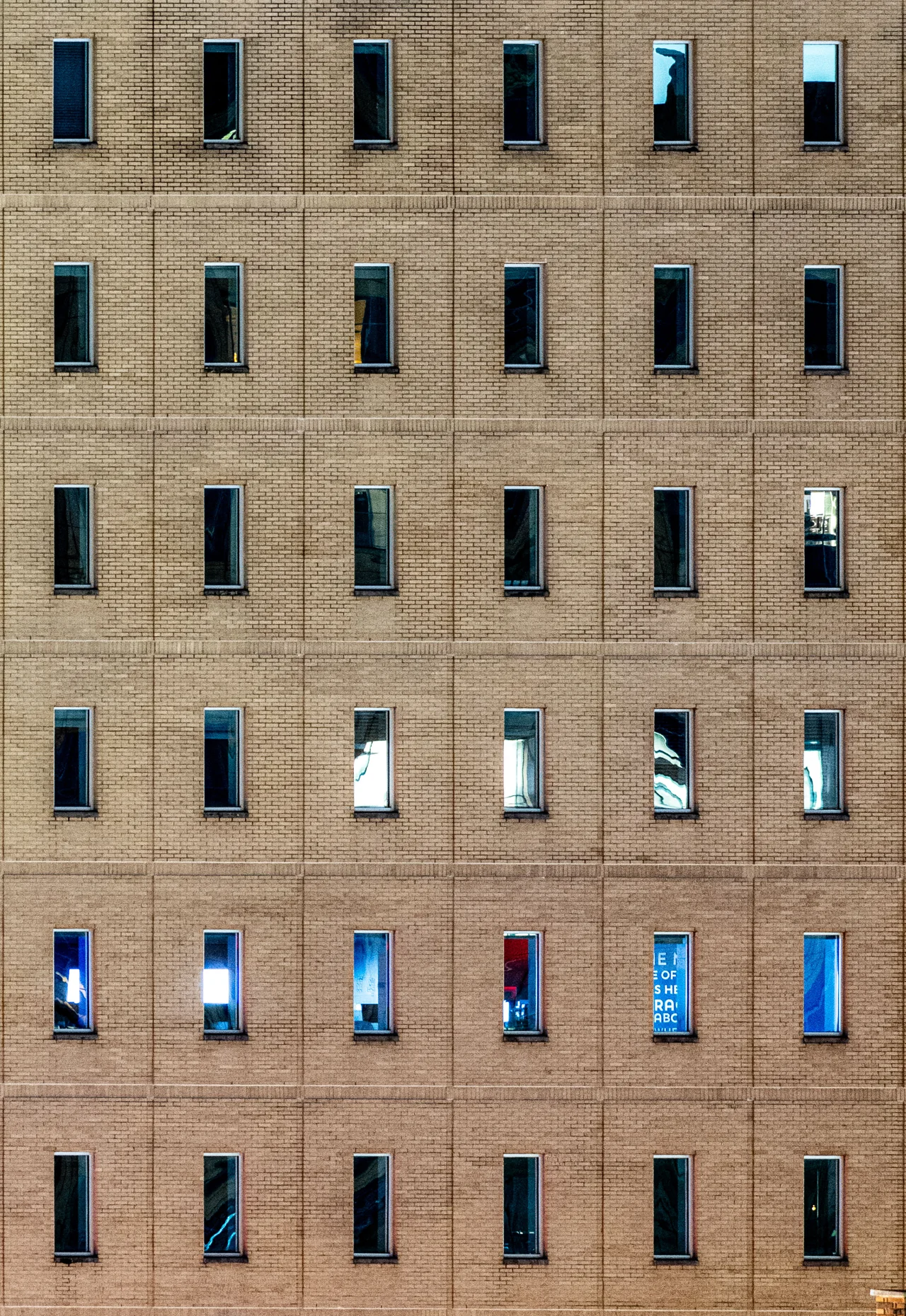 Repeated windows form a graphic pattern across a tan building facade.